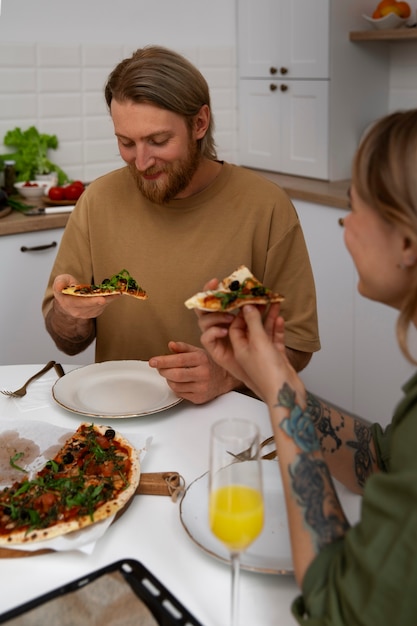 Free photo side view couple with delicious pizza