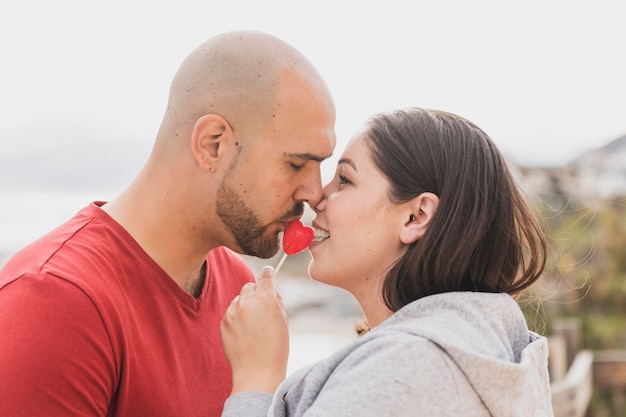 Free photo side view couple with heart lollipop