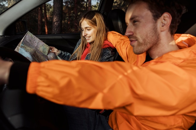 Free photo side view of couple with map inside car going on a road trip