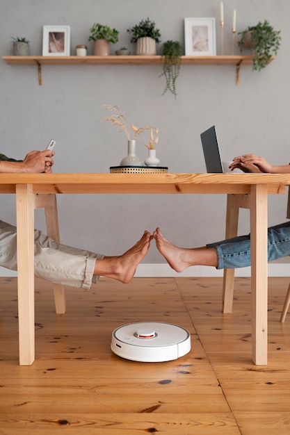 Side view couple with robotic vacuum cleaner