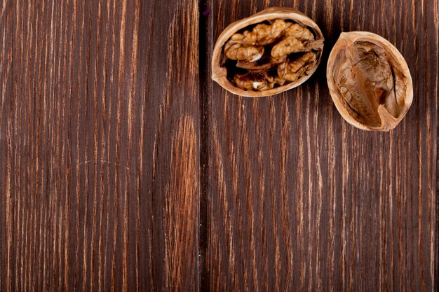 Side view of cracked walnut on wooden background with copy space