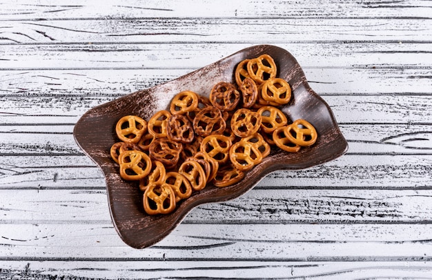 Side view crackers in brown plate on white wooden horizontal