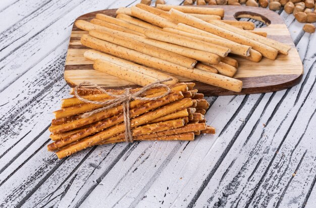 Side view of crackers on wooden cutting board on white  horizontal