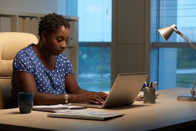 Side view of Cuban woman replying to emails at work in the evening