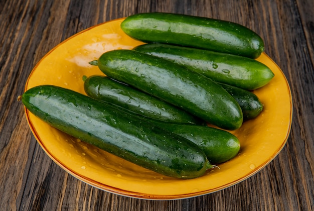 Free photo side view of cucumbers in plate on wooden surface