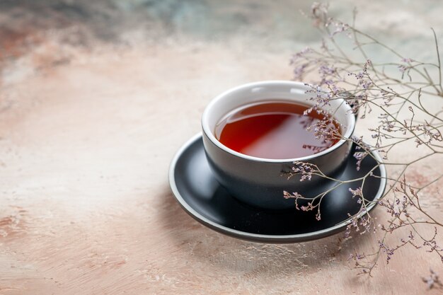 Side view a cup of tea a cup of tea on the black saucer next to the tree branches