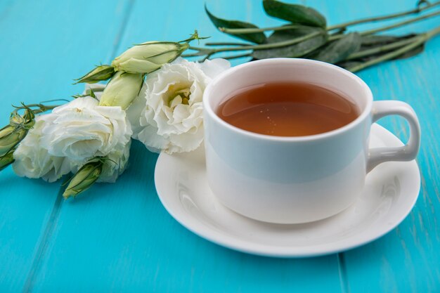 受け皿のお茶と青い背景の花の側面図