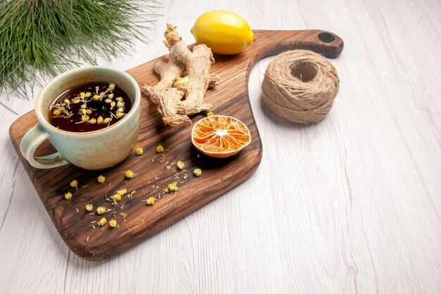 Side view a cup of tea white cup of herbal tea lemon on the wooden kitchen board next to the spruce branches