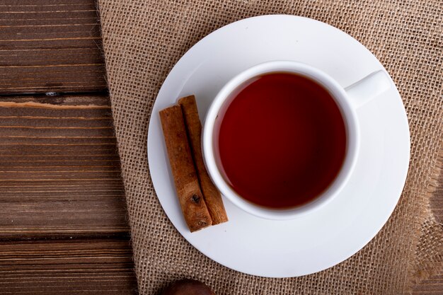 Side view of a cup of tea with cinnamon sticks on a rustic