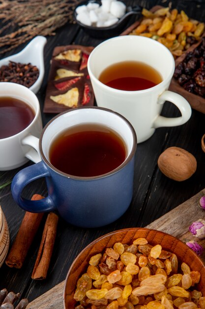 Side view of cup of tea with dried raisins in a wood bowl on rustic