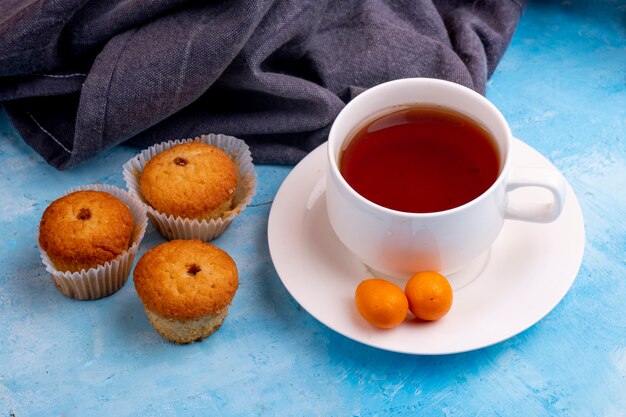Вид сбоку чашку чая с вкусной булочки на синем столе
