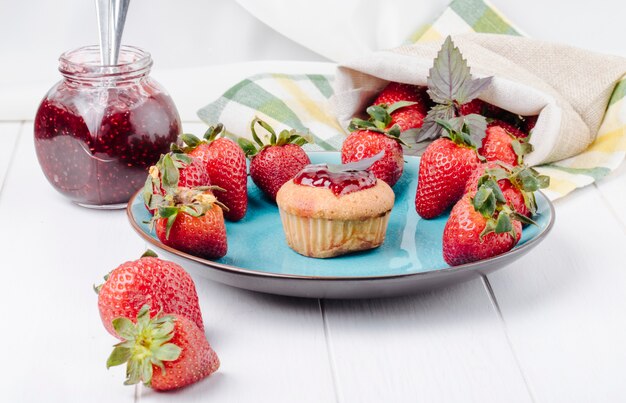 Side view cupcake with strawberry jam basil and fresh strawberry on a plate