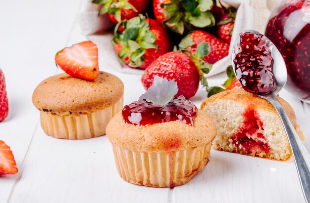 side view cupcakes with strawberry jam basil and fresh strawberry on white background