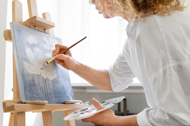 Side view of curly-haired woman painting at home