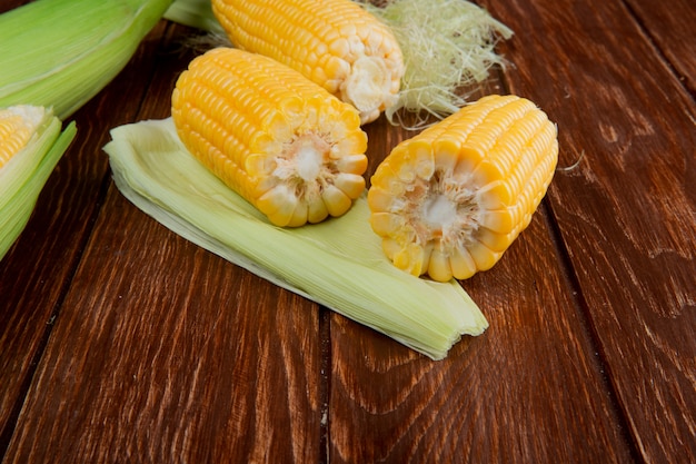 Side view of cut and whole corns with shell on wooden table