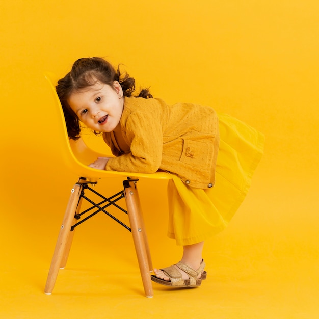 Free photo side view of cute child posing with chair