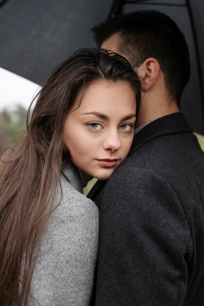 Side view cute couple under umbrella