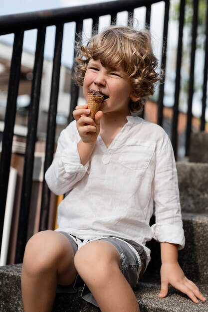 Вид сбоку милый ребенок ест мороженое