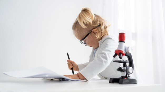 Side view of cute toddler with lab coat and microscope