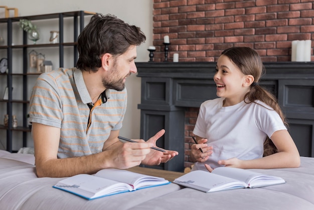 Free photo side view dad teaching girl to write