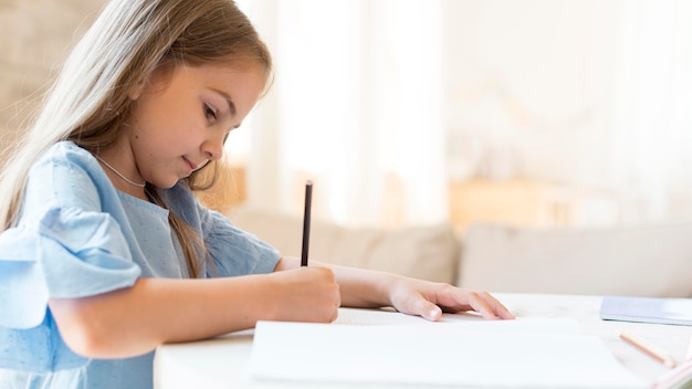 Side view of daughter doing her homework at home