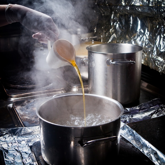 Side view deep pot with boiling water and oil and foil in stove