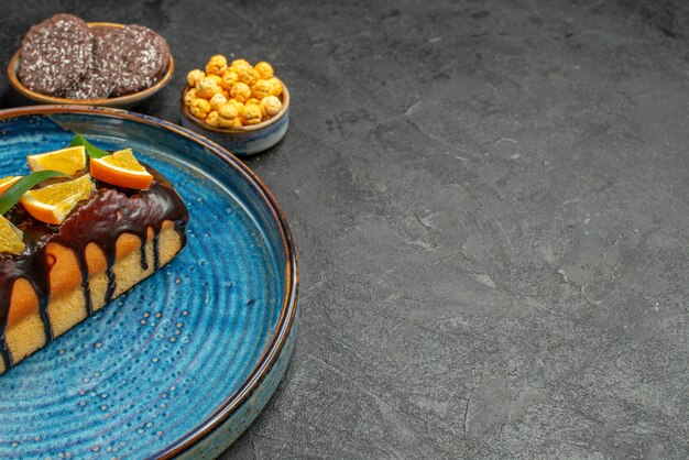 Side view of delicious cakes on blue tray and biscuits on dark table