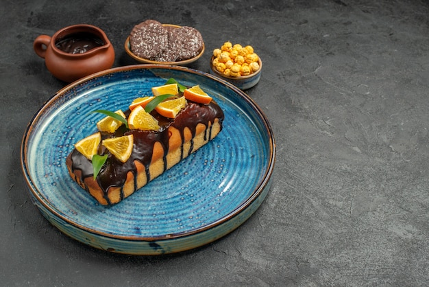 Side view of delicious cakes on blue tray and biscuits on dark table