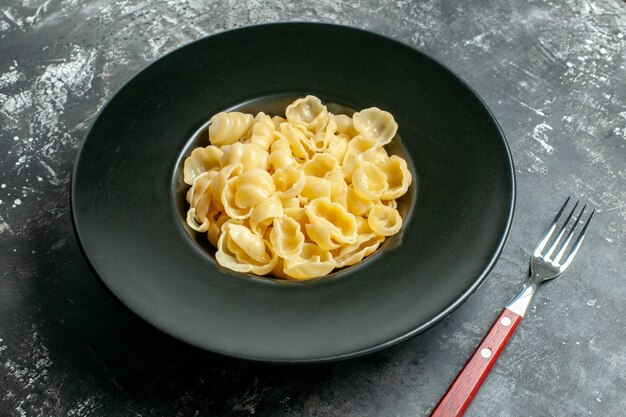 검정 접시에 있는 맛있는 콘치글리와 회색 배경에 칼의 측면