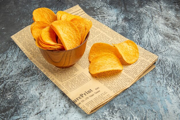 Side view of delicious homemade chips on newspaper on gray table