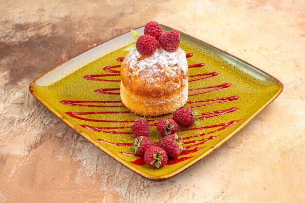 Side view of delicious mini cake with fruits on a green plate on mixed color background