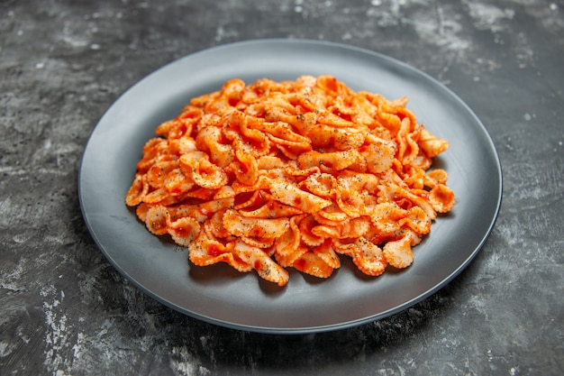 Vista laterale di una deliziosa pasta su un piatto nero per cena su sfondo scuro