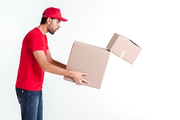 Side view delivery boy holding parcel post boxes and drops one