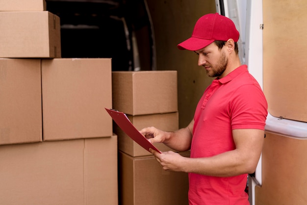 Free photo side view delivery man checking packages list