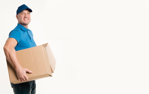 Side view of delivery man smiling while holding cardboard boxes