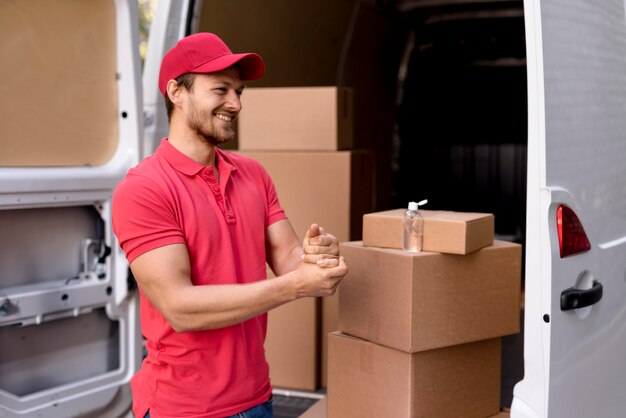 Side view delivery man using hand sanitizer