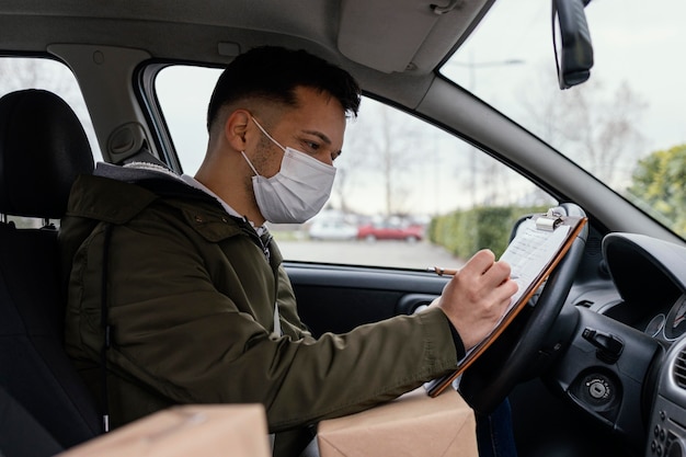 Side view delivery man with mask in car