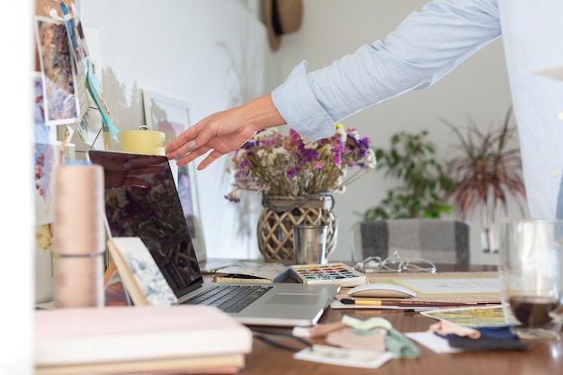 Free photo side view of desk with laptop and flowers