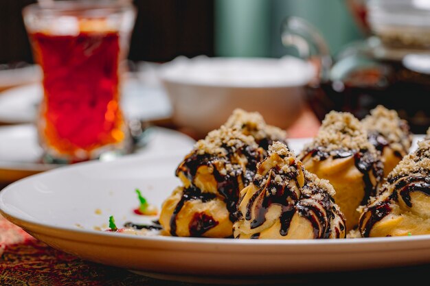 Side view dessert profiteroles with chocolate icing and grated nuts