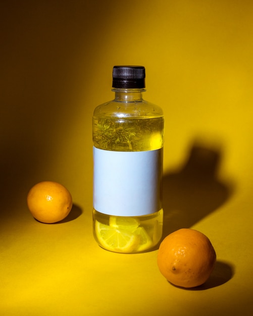 Free photo side view of detox drink with lemon in a bottle on dark yellow