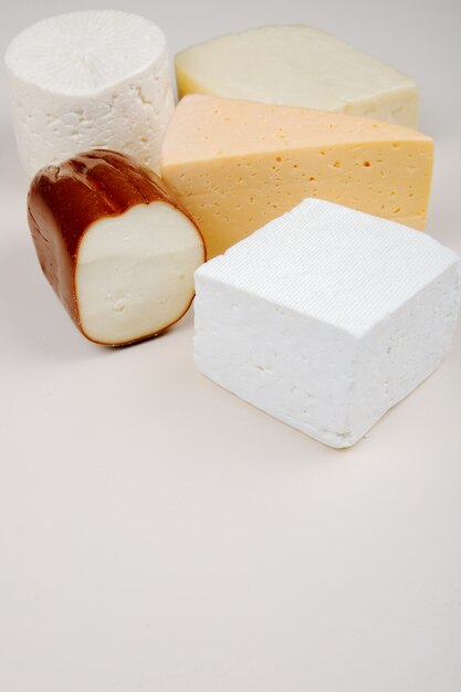 Side view of different kind of cheese on white table