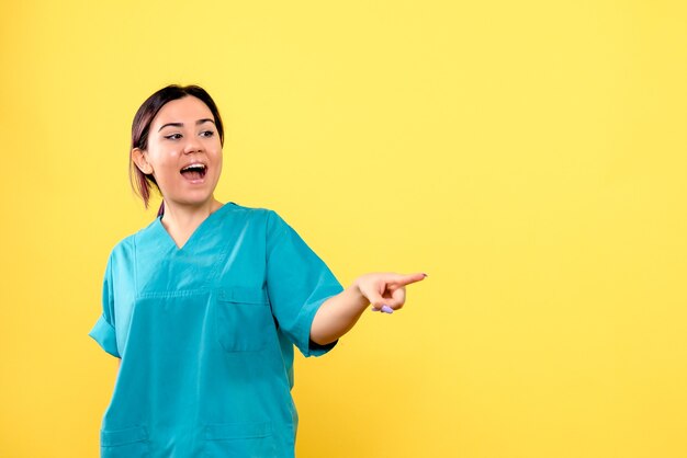 Side view of a doctor in blue medical uniform points to the side