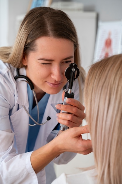 Free photo side view doctor checking patient's eyes