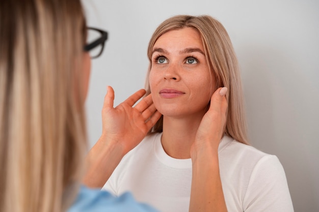 Side view doctor checking patient's neck