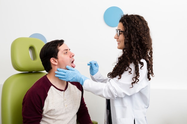 Доктор вид сбоку осматривает горло пациента