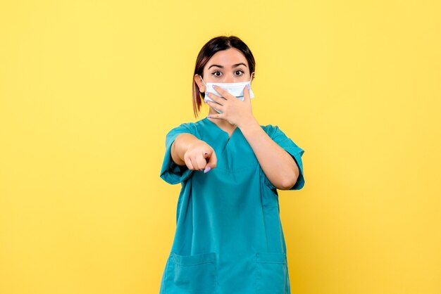 Side view of a doctor in mask points forward