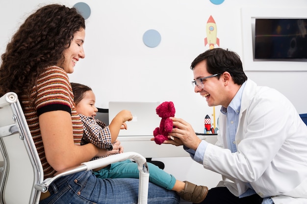 Free photo side view doctor playing with baby boy