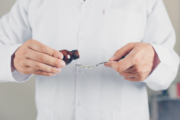 Side view a doctor pouring syrup for someone. horizontal