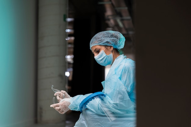 Free photo side view doctor in protective wear holding her goggles