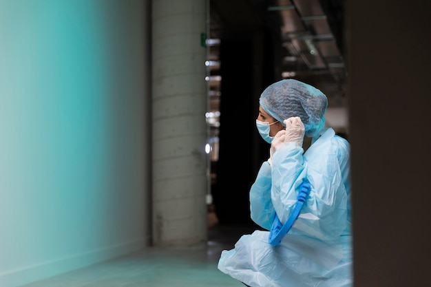 Free photo side view doctor putting on a face mask with copy space